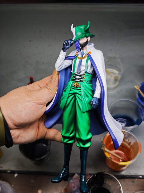 Hand-held view of Page One showing his horned hat, black mask, purple braid, green suspenders and blue-lined white cape.