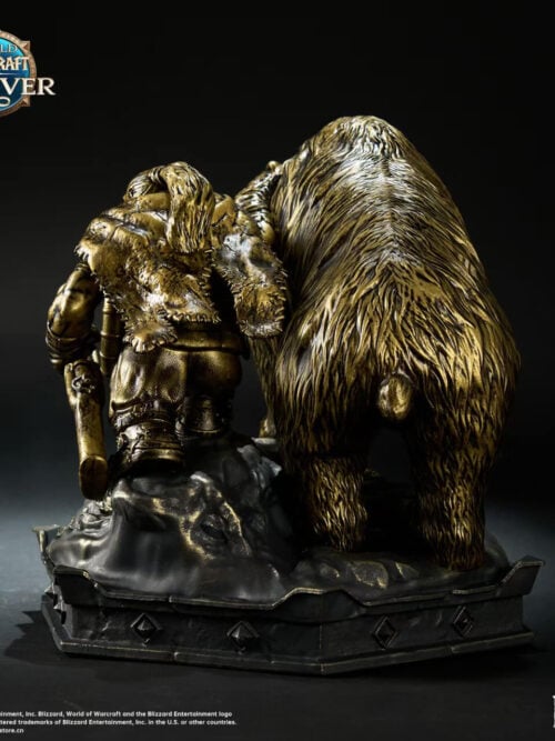 Rear view of the bronze-colored dwarf hunter and bear statue, showing the hunter's clothing, bear's tail and rocky base.