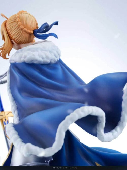 Rear detail of Altria Pendragon's braided blond bun, blue hair ribbon and sweeping blue cloak with sculpted white trim.