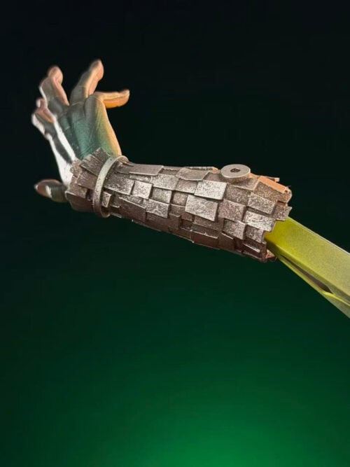Close-up of Katsuki Bakugo's revised right forearm with layered silver-gray detailing and an open green-gloved hand.