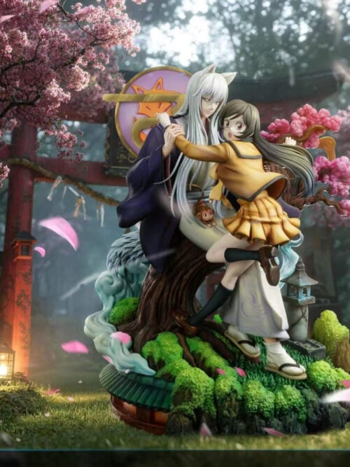 Long-haired Tomoe and Nanami Momozono on a tree-and-rock base with pink blossoms and a stone-style lantern, against a shrine backdrop.