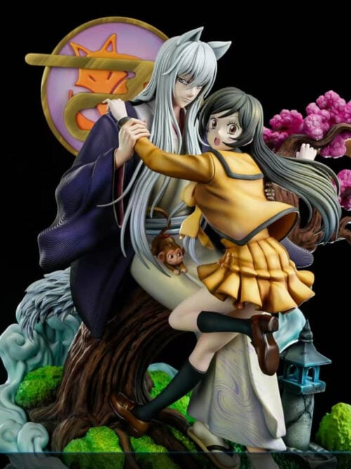 Long-haired Tomoe beside Nanami in her yellow school uniform, with pink blossoms and pale-blue effects against a black background.