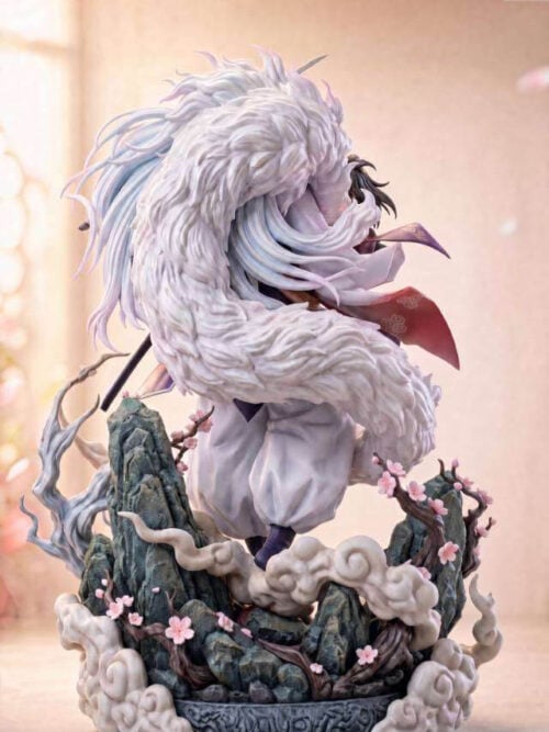 Rear view of the Sesshomaru and Rin statue, showing sweeping white fur, flowing hair and blossom-covered rocks above the cloud base.
