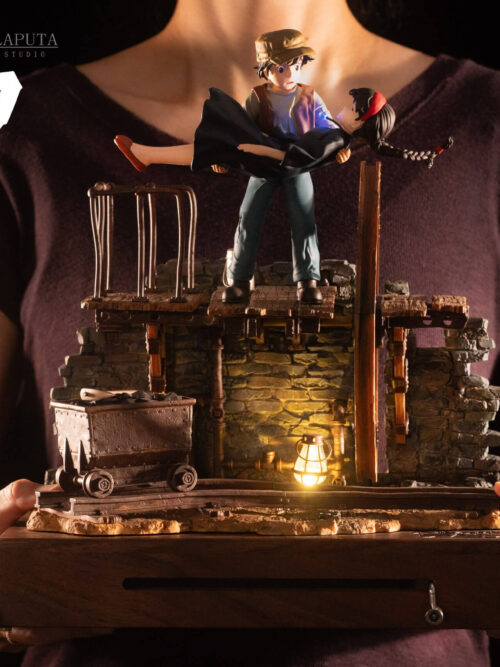Person holding the Sheeta and Pazu music box with its wooden housing and crank visible; dimensions shown are 32 × 25 × 34 cm.