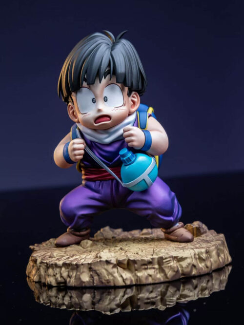 Young Son Gohan prototype with wide eyes and an open mouth, gripping backpack straps beside a turquoise canteen on a rocky base.