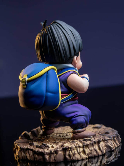 Rear three-quarter view of Son Gohan showing a blue backpack with yellow trim, black hair, purple trousers and a rocky base.
