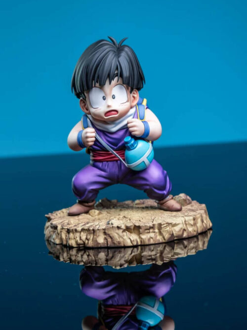 Young Son Gohan prototype crouching on a rocky base against a blue background, with a turquoise canteen and reflection below.