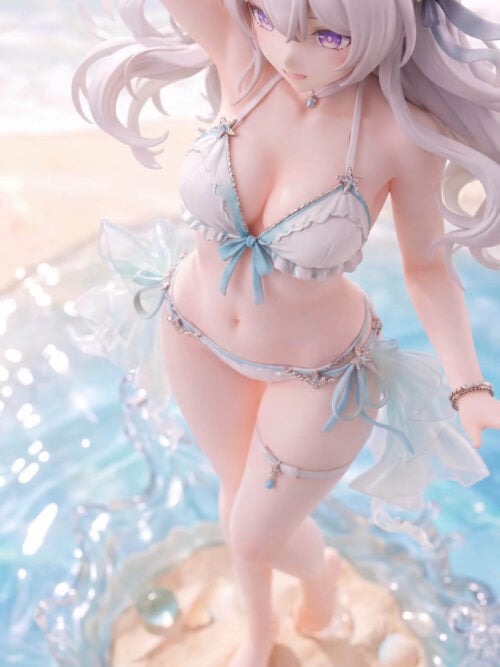 High-angle view of Firefly's smiling face, white ruffled swimsuit, aqua bows and sandy wave-effect base.