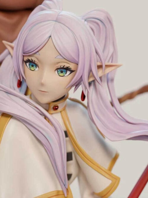 Frieren portrait detail showing pale twin tails, pointed ears, red earrings and a gold-trimmed white cape beside her staff.