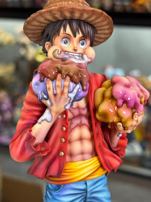 Front close-up of Luffy with puffed cheeks, icing around his grin and two oversized cakes held in his hands.