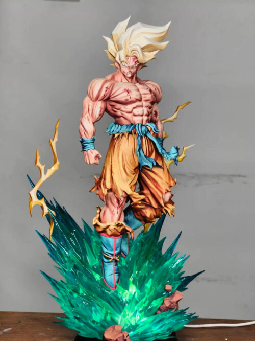 Son Goku statue with golden hair and torn orange trousers above a teal energy base glowing bright green from within.