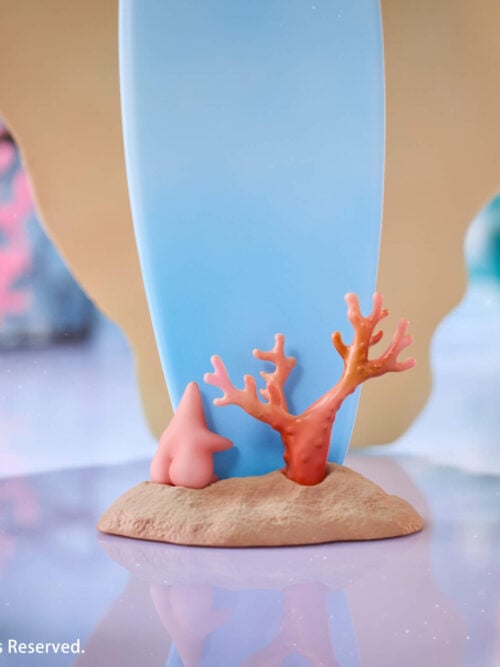 Rear support detail of the Summer Beach Date display, showing a blue support on a sand-textured foot with coral decorations.