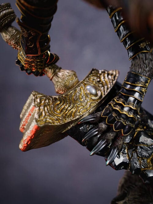 Maliketh gripping the sword hilt beside an ornate gold-colored guard, with a clawed foot braced against the black blade.