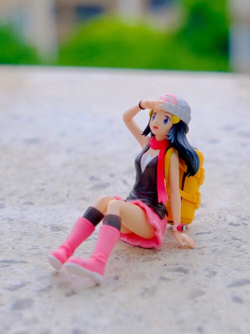 Dawn figure seated with pink boots extended forward, one hand raised to her forehead and a yellow backpack behind her.