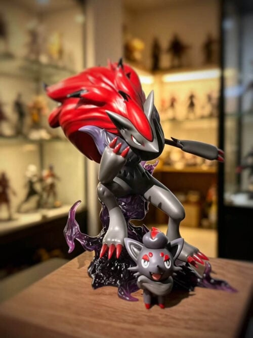 Three-quarter view of Zoroark with a sweeping red mane and raised claws above purple effects, with Zorua standing in front.