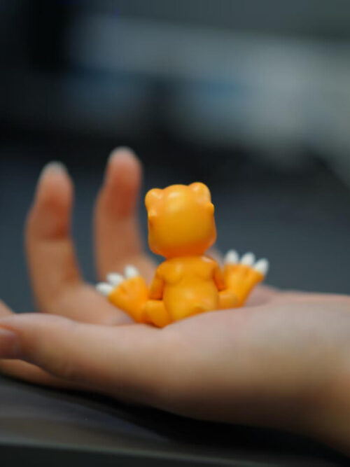 Rear view of the seated Agumon MH figure resting in an open palm, with an MH 4.5 cm label in the upper right.