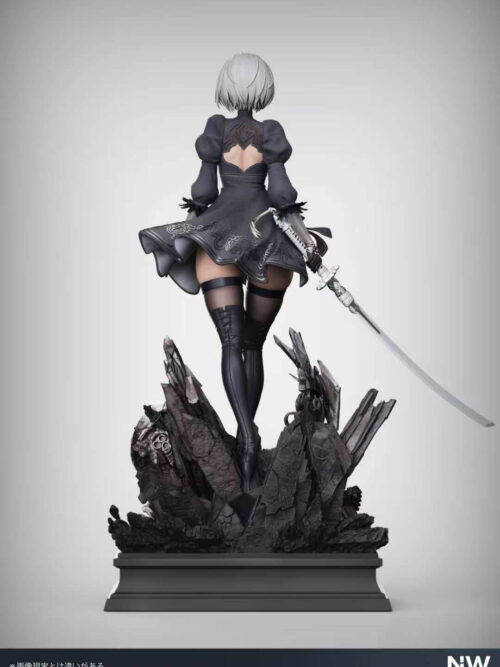 Rear view of 2B showing the flared patterned black skirt, open-back costume, tall boots, sword and rubble base.