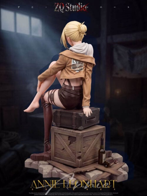 Rear view of Annie Leonhart showing her blonde bun, hood, jacket emblem and seated pose above a crate and cracked paving.