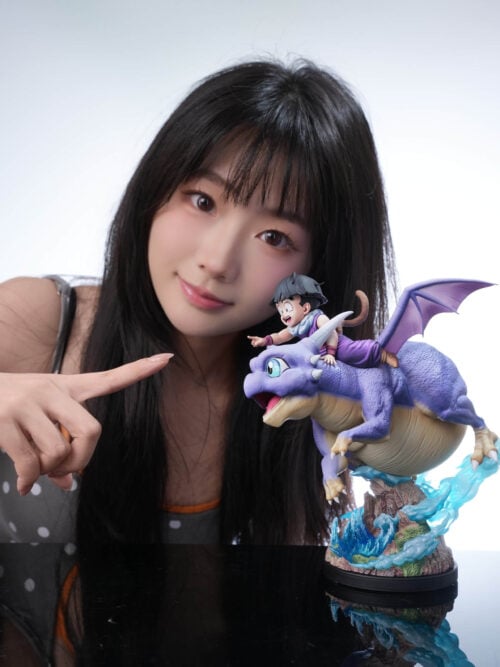 A person points toward a side view of Son Gohan riding Icarus on a rocky base with blue effects.