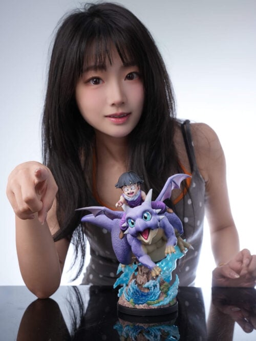 A person points beside the Son Gohan and Icarus statue displayed with its complete scenic base on a reflective table.