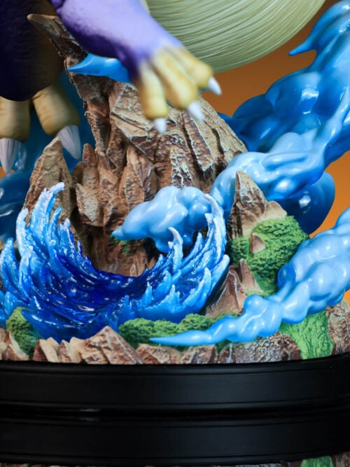 Close-up of blue waves and pale blue effects surrounding rocky peaks and green vegetation on a black plinth.