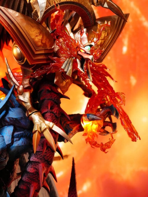 Close-up of The Winged Dragon of Ra with golden armor, illuminated eyes, and translucent red flames above Obelisk the Tormentor's glowing left palm