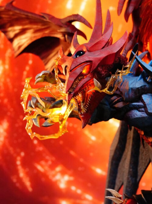 Close-up of Slifer the Sky Dragon's dual-jawed red head with illuminated eyes and mouth beside translucent yellow lightning around Obelisk the Tormentor's right hand