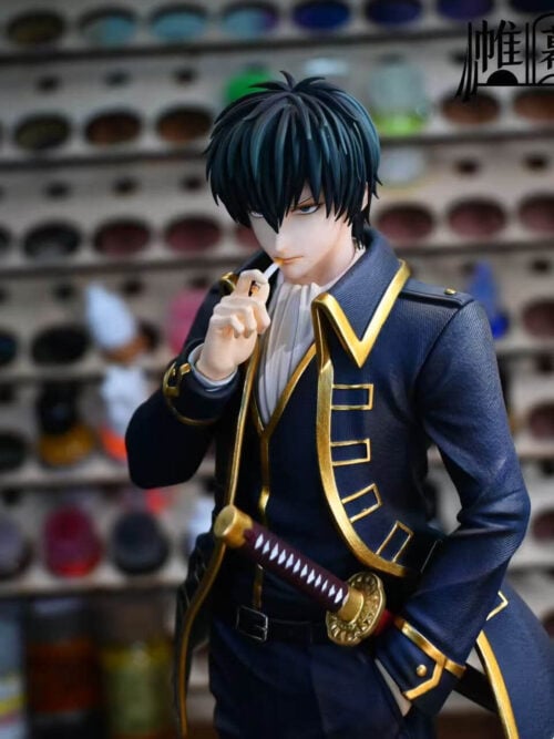 Three-quarter upper-body view of the Toushirou Hijikata statue highlighting the cigarette in his right hand, gold-edged coat lapels, and katana hilt at his waist