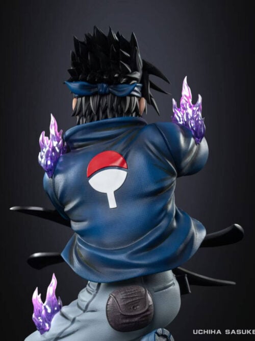 Rear close-up view of the Sasuke Uchiha statue showing the red-and-white Uchiha crest on his blue shirt, tied headband, waist pouch, shuriken blade tips, and translucent purple flame effects.