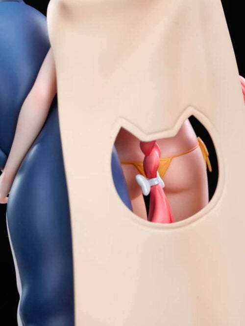 Rear close-up view of the Hanaoka Yuzu statue showing the cat-head cutout on the back of her beige cape framing her pink braid and yellow bikini bottom while her left arm rests against the blue plush companion