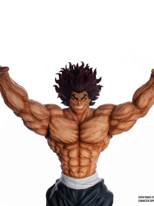 Upper-body front close-up of the SuperPunch Studio Yujiro Hanma statue against a white background, showing his grinning expression, heavy dark brows, veined torso, and raised arms.