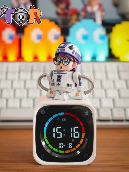 Vertical view of TOR Studio Arale Series Vol. 28 WCF-scale figure showing Arale Norimaki with purple hair and round black glasses inside a white-and-blue cylindrical robot body with a domed helmet, posed atop a white digital clock.