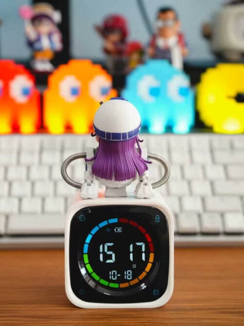 Rear view of TOR Studio Arale Series Vol. 28 figure standing on a white digital clock, showing the white domed helmet with a blue band, purple hair covering the back, and symmetrical coiled silver hose arms.