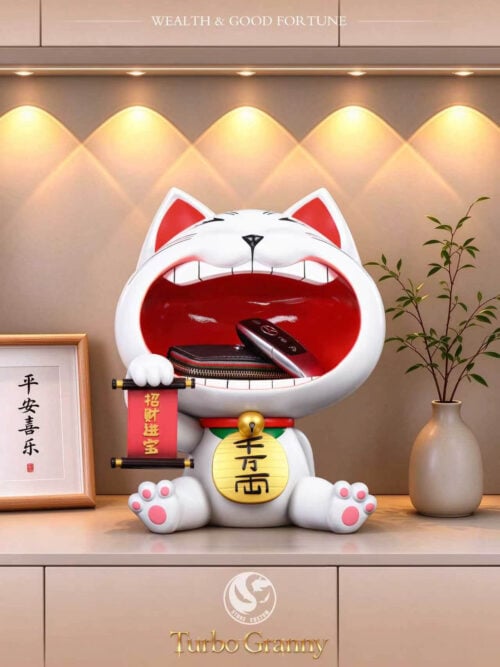 Stone Custom Studio Turbo Granny maneki-neko entryway display piece holding a wallet and car key fob on a lit shelf next to a framed print and vase.