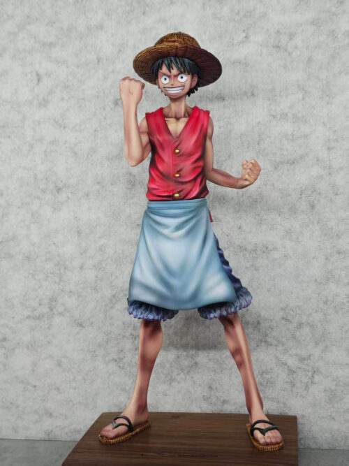 Monkey D. Luffy apron figure with one clenched fist beside his face and the other held lower, wearing a straw hat and sandals.