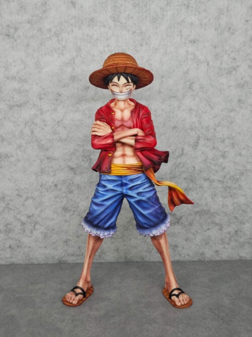 Full front view of Luffy with crossed arms, a broad grin, straw hat, red jacket, blue shorts and a trailing yellow sash.