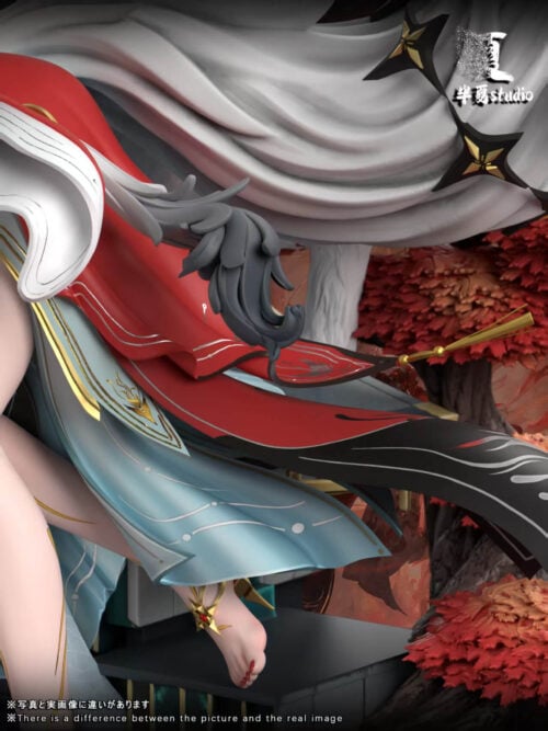 Close-up of Hsin's flowing red, black and pale blue costume panels, with gold-colored tassels and red foliage behind.