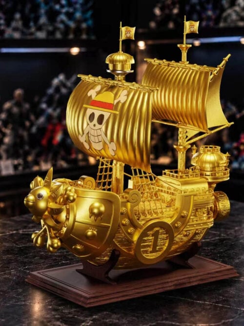 Gold Version Thousand Sunny with gold-colored sails and hull, a colored skull-and-crossbones sail emblem and a brown rectangular stand.