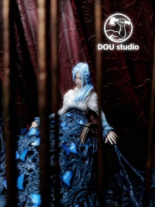 Angled close-up of Sophia Monad through bronze-toned cage bars, showing blue hair, a pale blouse, lowered hands and butterfly-covered web-like forms.