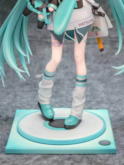 Detail of Hatsune Miku's white leg warmers, turquoise platform shoes and shoulder bag above a teal-and-white circular platform and square base.