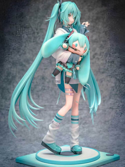Three-quarter view of Hatsune Miku holding a large Miku doll, with long sweeping twin-tails and turquoise platform shoes on a square base.