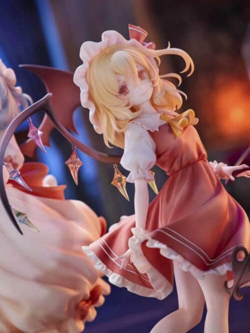 Flandre Scarlet in a red ruffled dress with a yellow bow and multicolored wing ornaments, with Remilia Scarlet behind her.