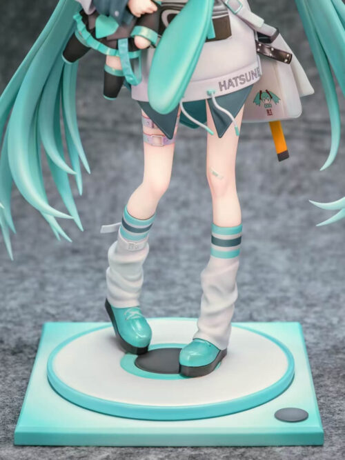Detail of Hatsune Miku's striped socks, loose white leg warmers and turquoise shoes above a circular platform on a square teal base.