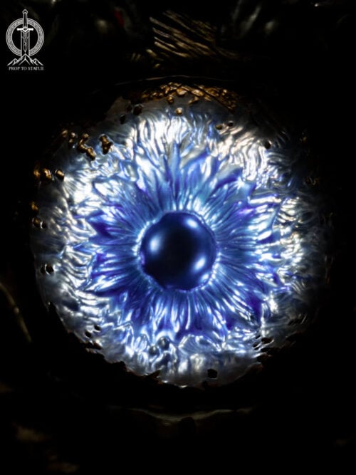 Tight close-up of the Oni Gauntlet's illuminated blue eye-like centerpiece, with radiating blue-white texture around a dark rounded center.