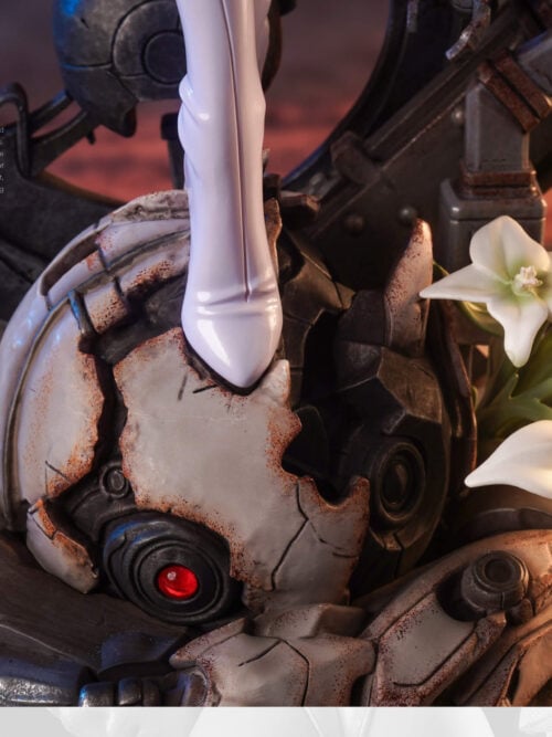 Base close-up showing 2B's boot on a cracked machine head with a red eye, surrounded by gears, damaged parts and white flowers.