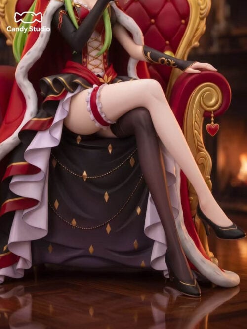 Detail of C.C.'s crossed legs, black heels, layered dress and gold throne armrest with a dangling red heart ornament.