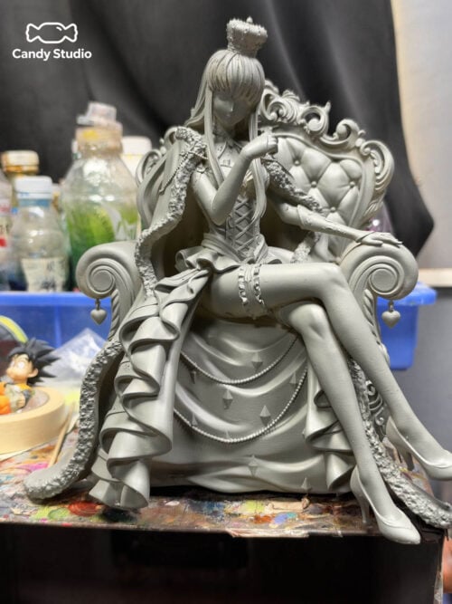 Unpainted gray C.C. throne sculpt on a workbench, showing the crown, crossed-leg pose, flowing cape and ornate chair.