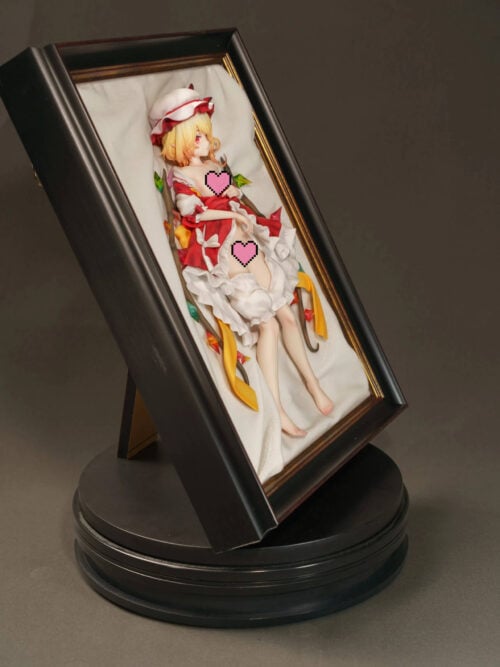 Censored angled photo of Flandre Scarlet's framed display, with the frame's rear support visible above a black circular platform.