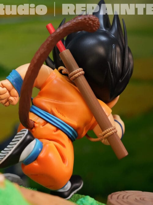 Rear close-up of running young Son Goku showing his curved brown tail, red staff in a brown carrier and blue sash.