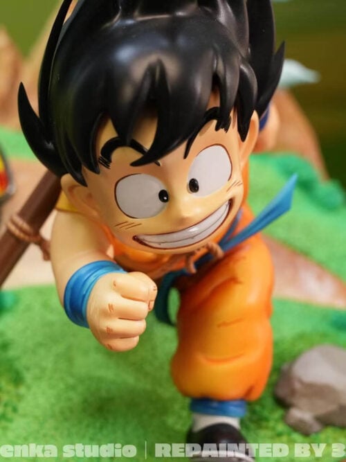Close-up from above of young Son Goku's broad grin, spiked black hair and forward fist, with a yellow car behind him.